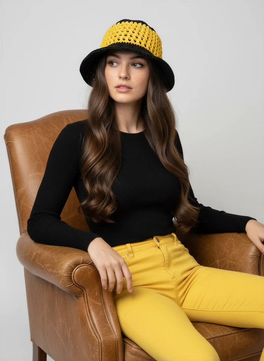 Chapeau Bobbydos – vue de face assise fauteuil – bucket hat crochet bicolore jaune noir résille ajourée – Cachalabibi
