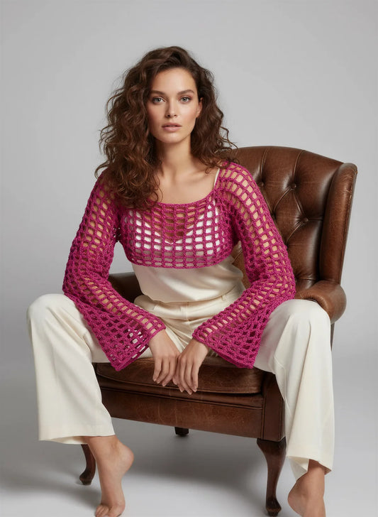 Crop Top Fuschiamo – vue de face assise fauteuil Chesterfield – crop top crochet fait main fuchsia manches évasées résille encolure bateau pose éditoriale – Cachalabibi