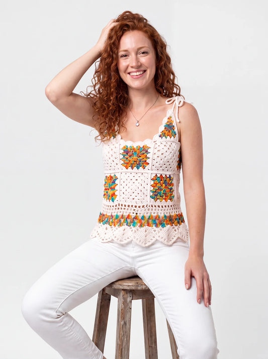 Haut en crochet Grannino blanc cassé, carrés granny orange vert jaune bleu, col cœur, de face sur un tabouret — Cachalabibi
