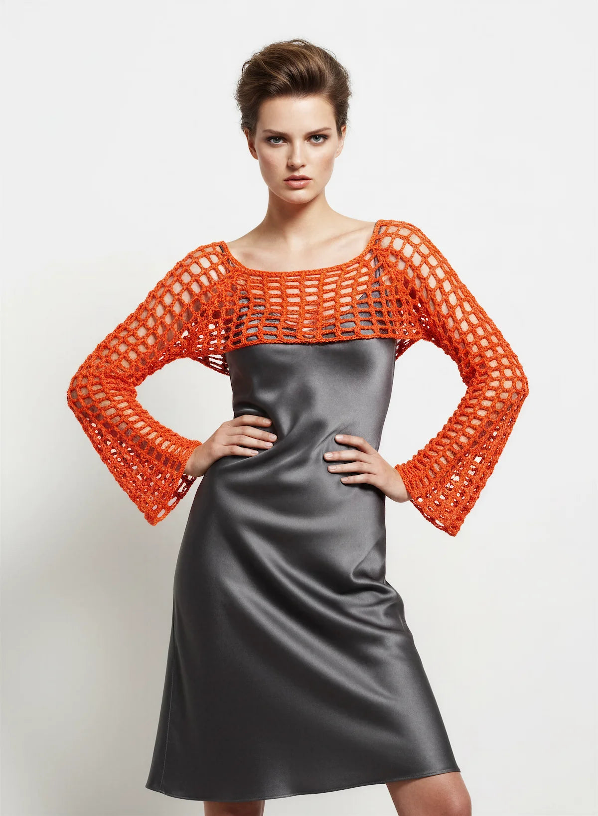 Crop Top Hibisca – vue de face mains sur hanches – crop top crochet fait main orange vif manches évasées résille encolure bateau sur robe satinée – Cachalabibi