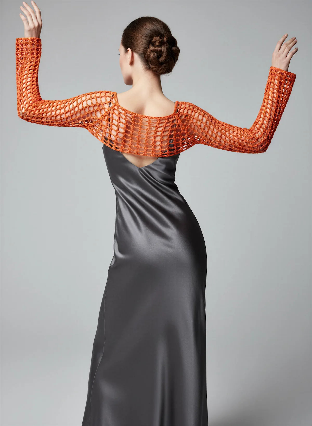 Crop Top Hibisca – vue de dos bras levés pose dansée – crop top crochet fait main orange vif manches évasées résille encolure dos bateau – Cachalabibi