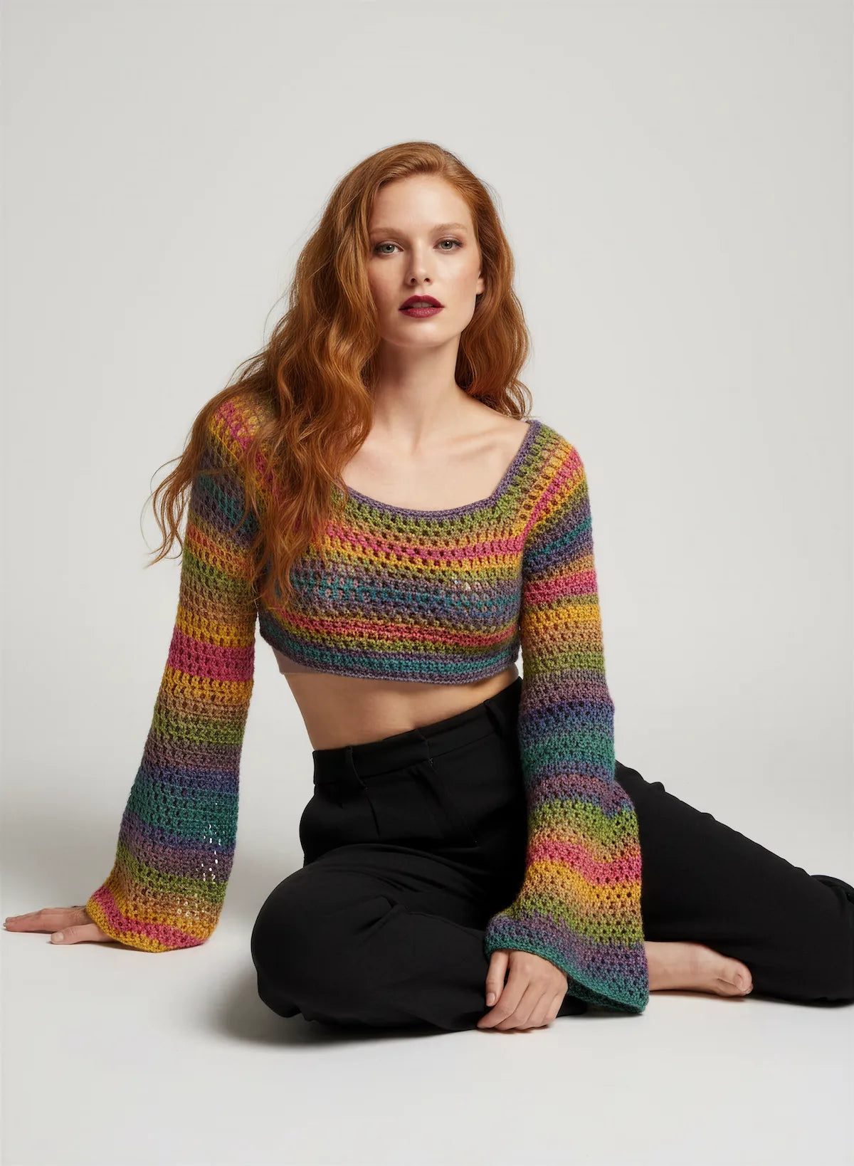 Crop Top Bobbyjam – vue de face assise – crochet fait main rayures arc-en-ciel manches évasées encolure bateau – Cachalabibi