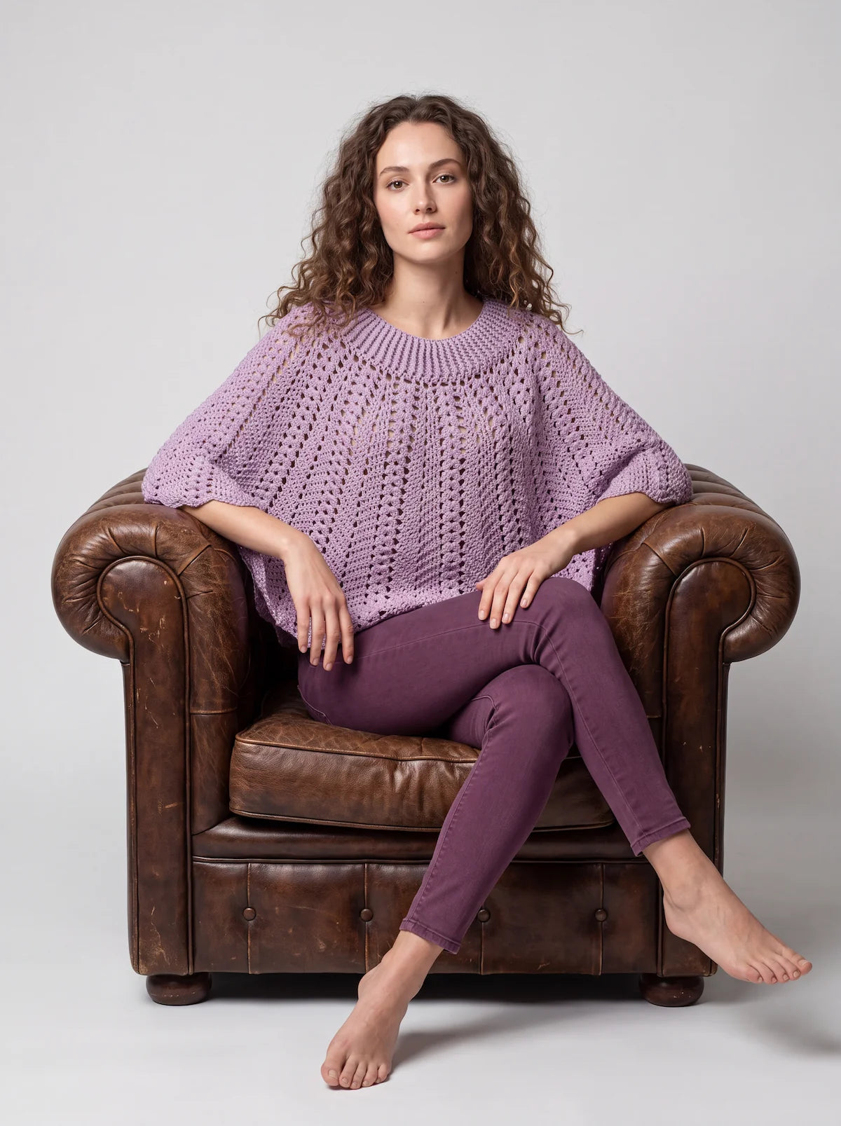 Poncho Violyne au crochet lilas, vue de face dans un fauteuil, point éventail et granny squares, manches évasées - Cachalabibi