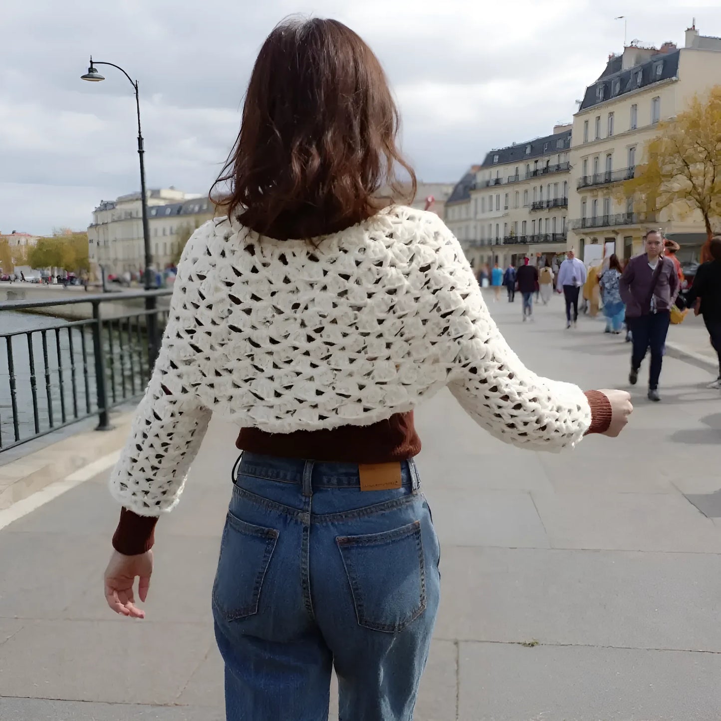 Pull court au crochet fait main Corto de Cachalabibi - écru - vue de dos sur les quais de Seine à Paris avec immeubles haussmanniens et promeneurs