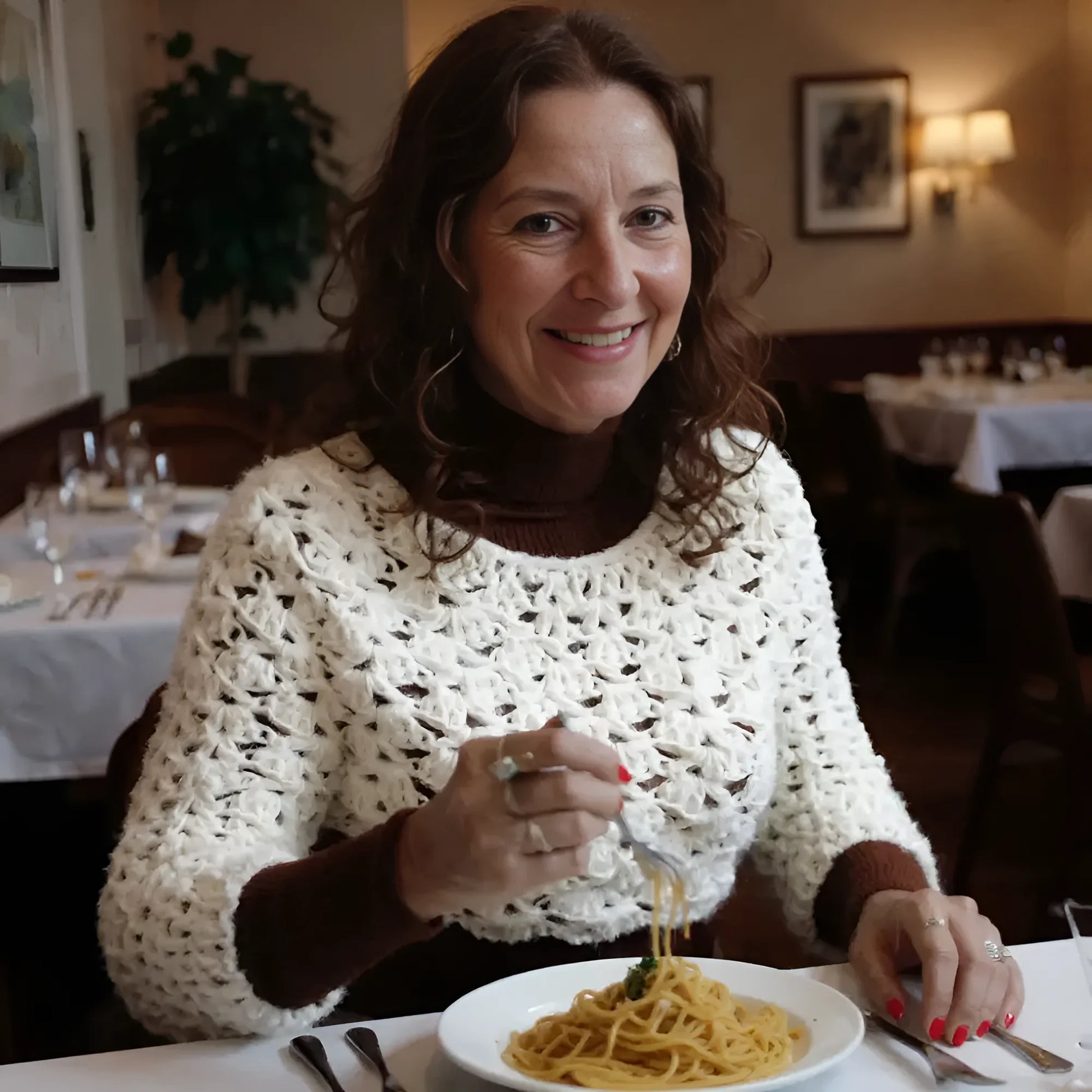 Pull court au crochet fait main Corto de Cachalabibi - écru - vue de face dans un restaurant italien avec tables nappes blanches