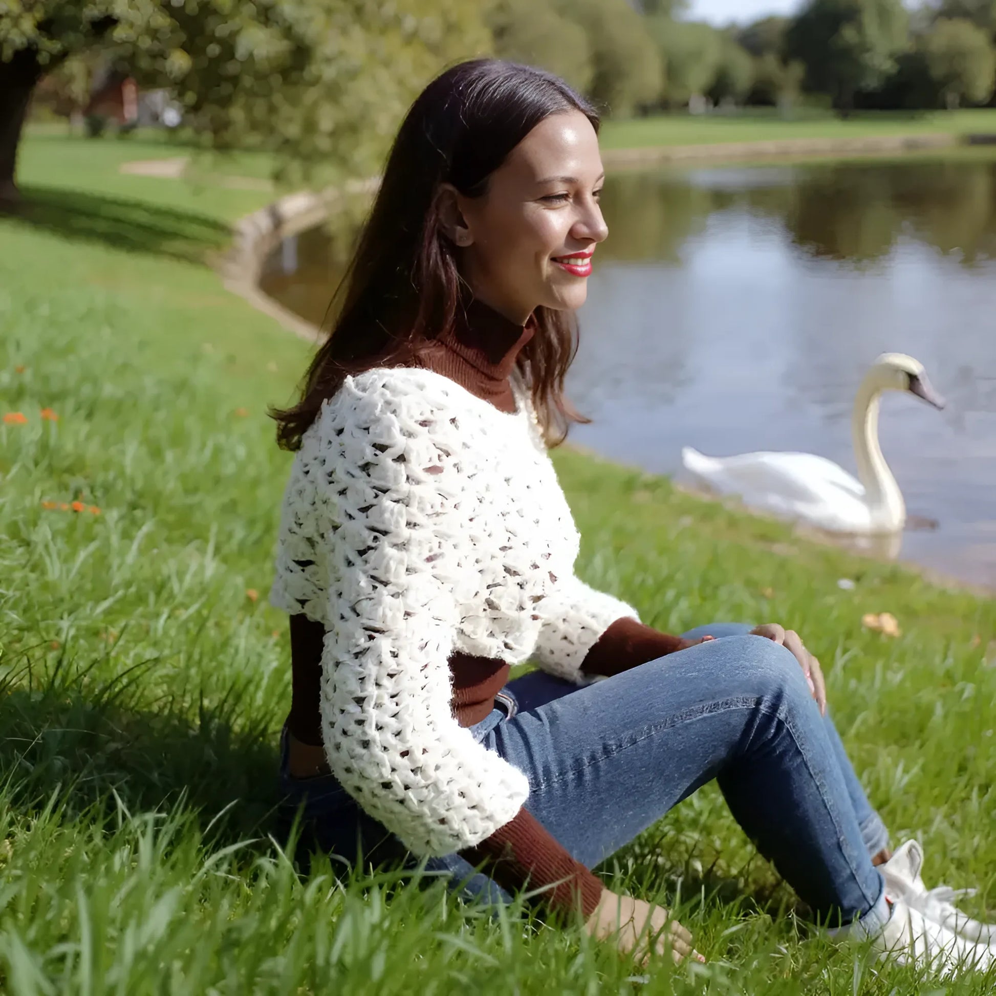 Pull court au crochet fait main Corto de Cachalabibi - écru - vue de profil au bord d'un étang avec cygne et verdure