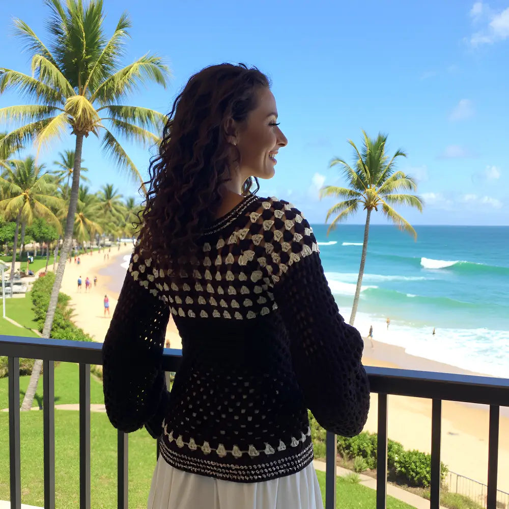 Pull au crochet fait main Damiana de Cachalabibi - noir - vue de dos au balcon avec vue sur la plage paradisiaque