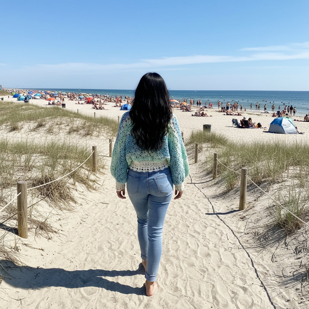 Pull au crochet fait main Fidji de Cachalabibi - turquoise - vue de dos contemplant la plage animée avec parasols et baigneurs