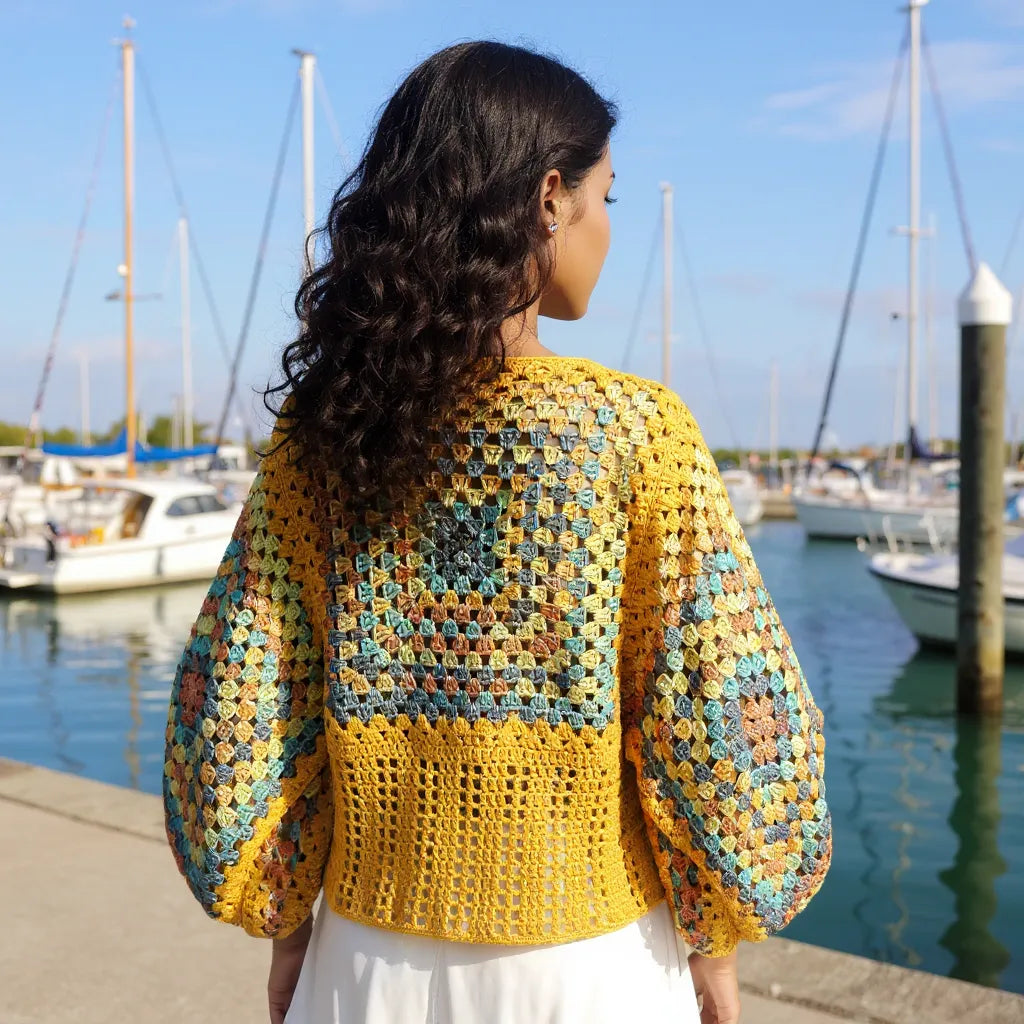 Pull au crochet fait main Labyrintho de Cachalabibi - jaune - Dos coloré avec des manches amples sur une femme dans une marina