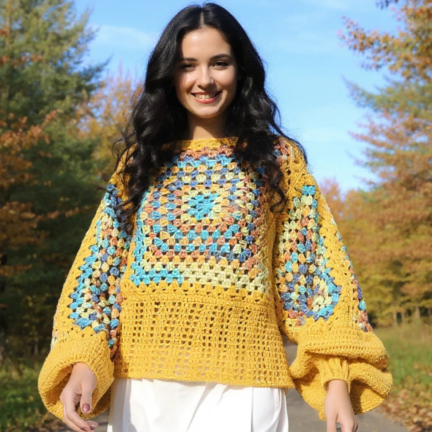 Pull au crochet fait main Labyrintho de Cachalabibi - jaune - vue de face sur une femme qui marche sur un chemin forestier