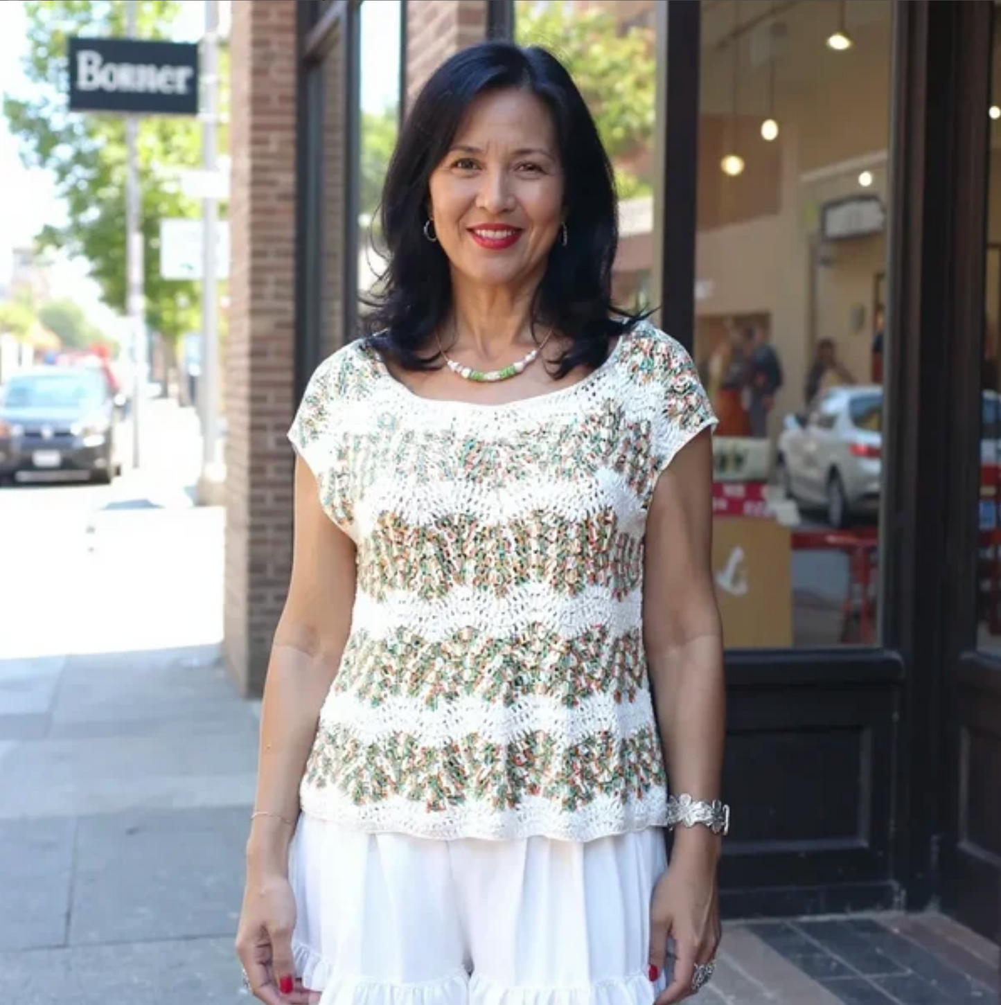 Pull au crochet fait main Azeitona de Cachalabibi - beige - Vue de face en rue commerçante, élégance estivale fabriquée en France