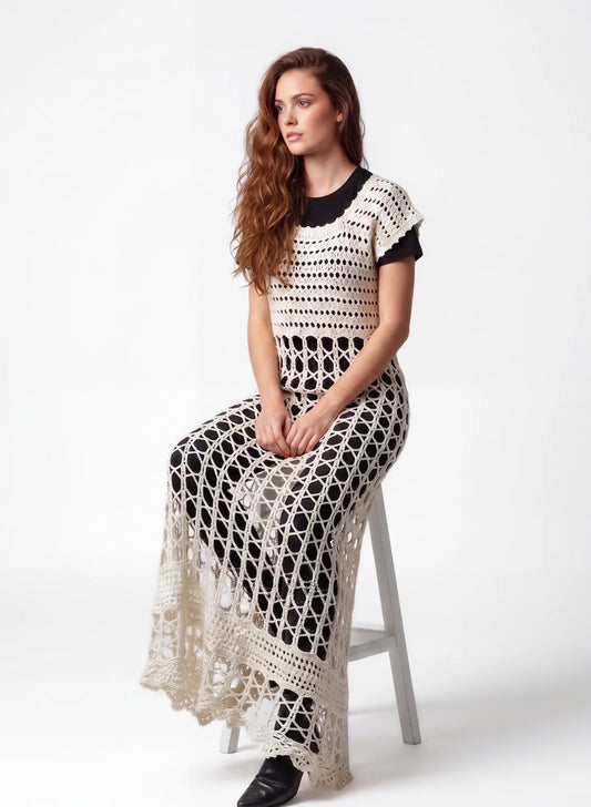 Robe crochet fait main Overdressy écru grandes mailles hexagones transparente sur noir - assise sur tabouret – Cachalabibi