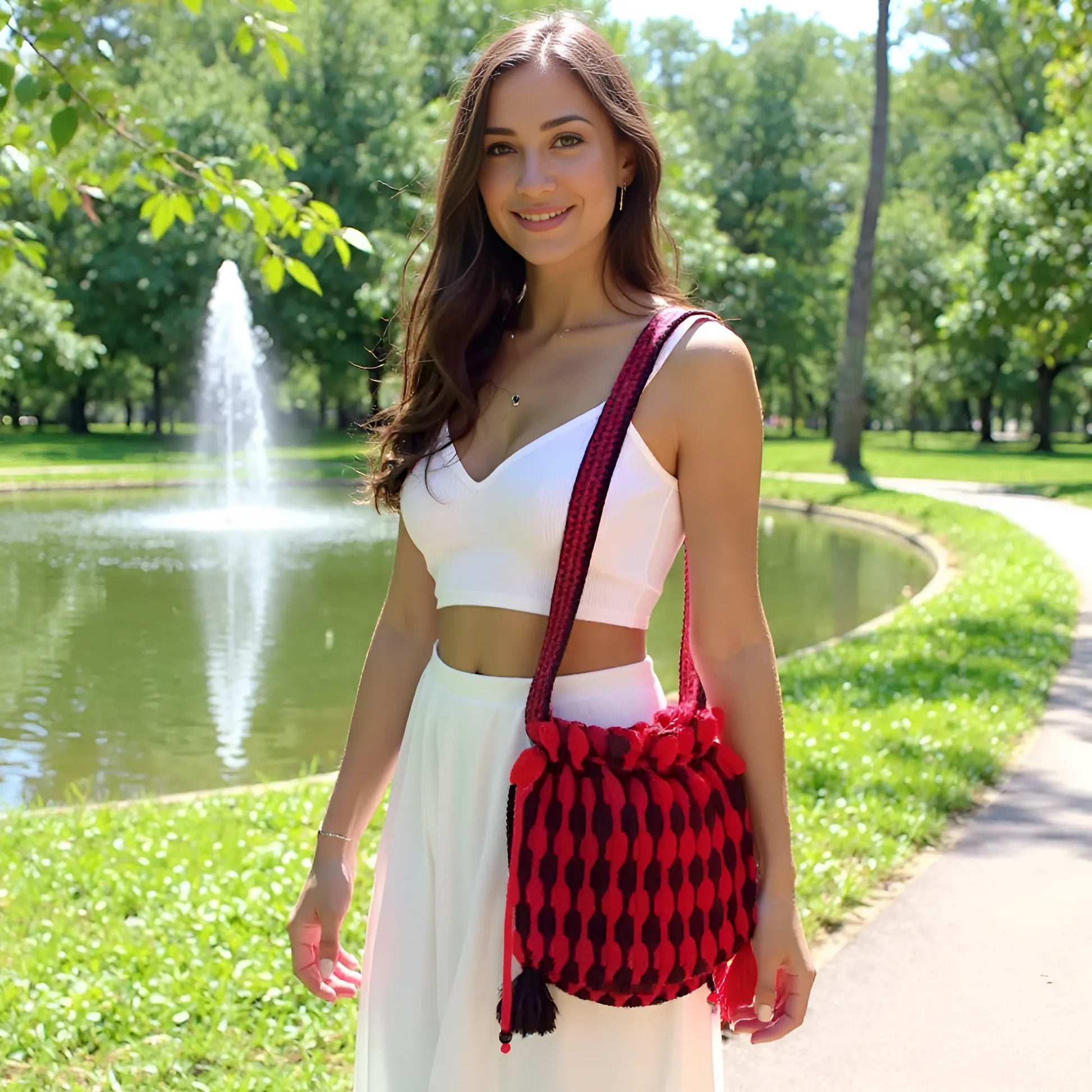 Sac à main au crochet fait main Rossonero de Cachalabibi - rouge et noir - vue de face en bandoulière au parc avec fontaine